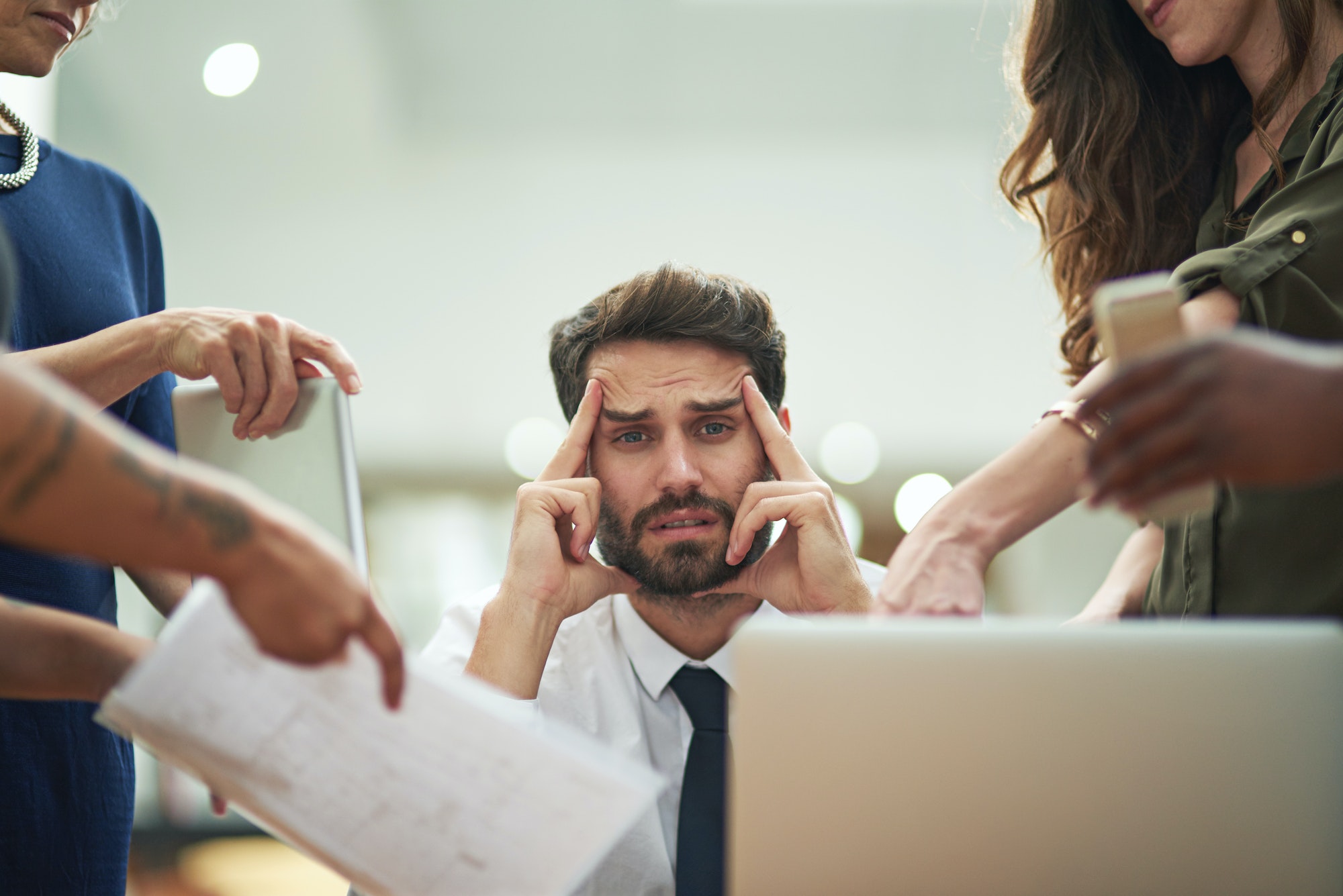 Cropped portrait of a young businessman feeling overwhelmed by his colleagues in the office